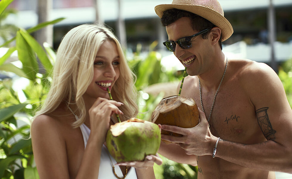 Couple smiling while drinking out of coconuts