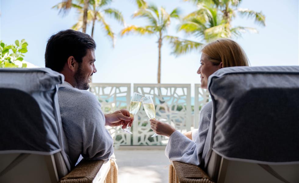 A couple smiling at one another while relaxing on a chair