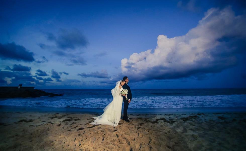 A bride and groom on the beach during dusk