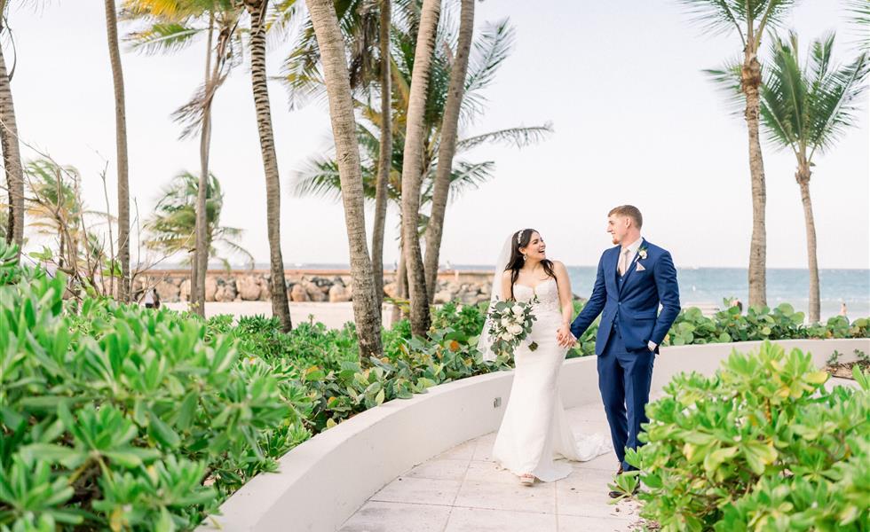 A bride and groom walking along the beach
