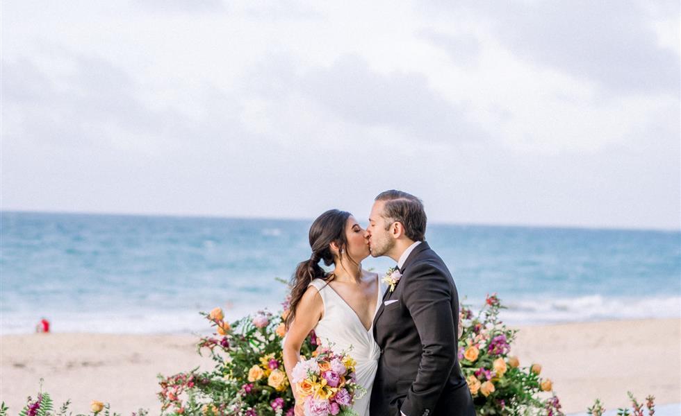 The bride and groom kissing on the beach