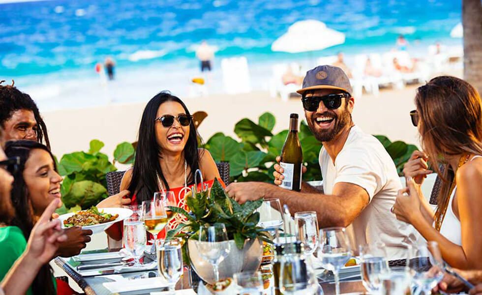 Group of friends eating around a table along the beach