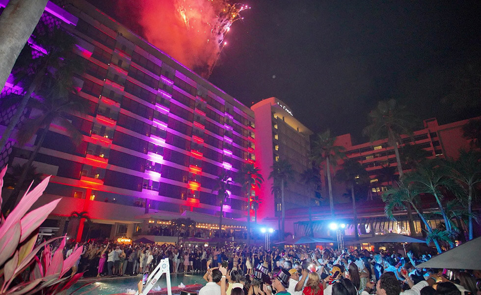 La Concha Resort guests gathered around the pool in party attire as a fireworks display is going off