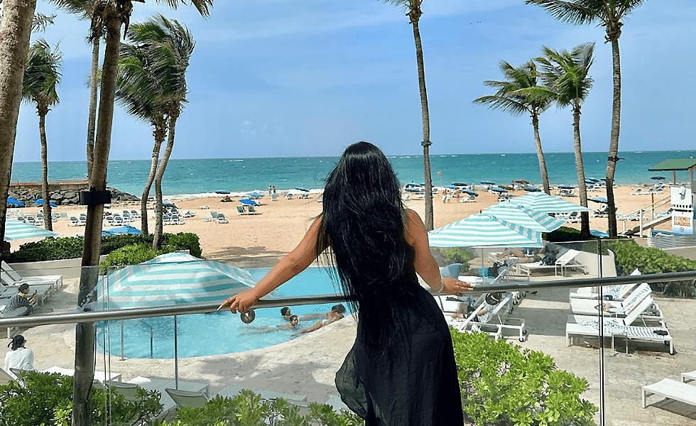 Woman in a flowy dress overlooking the pool area and beach