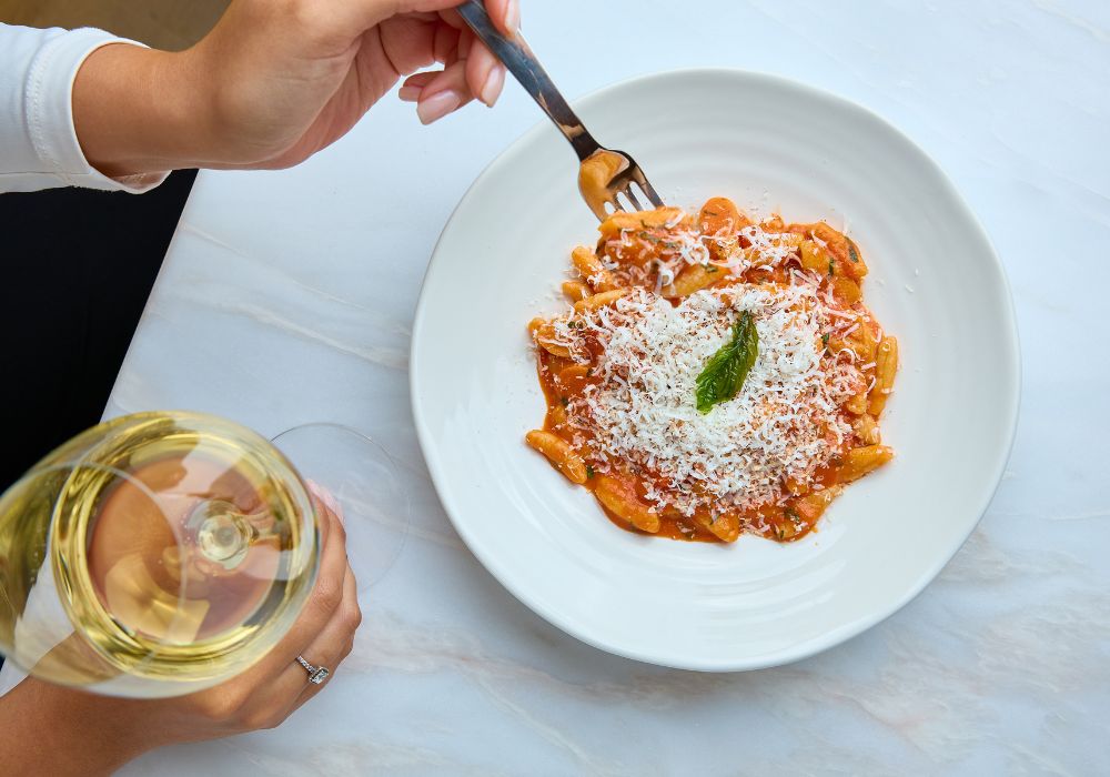 Pasta dish with glass of white wine from above