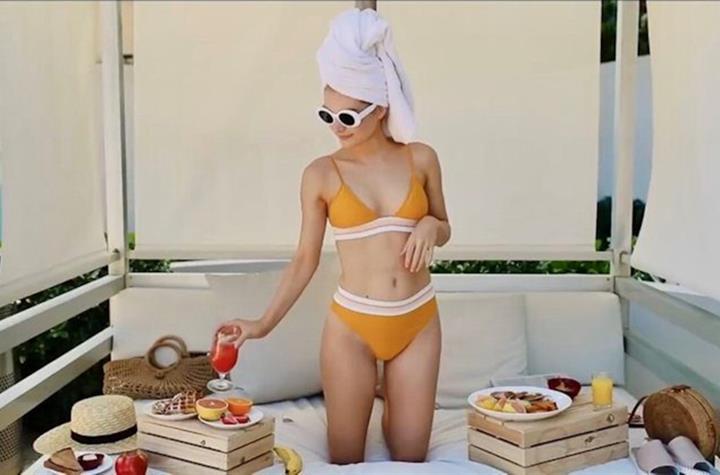 A woman enjoying food under a cabana