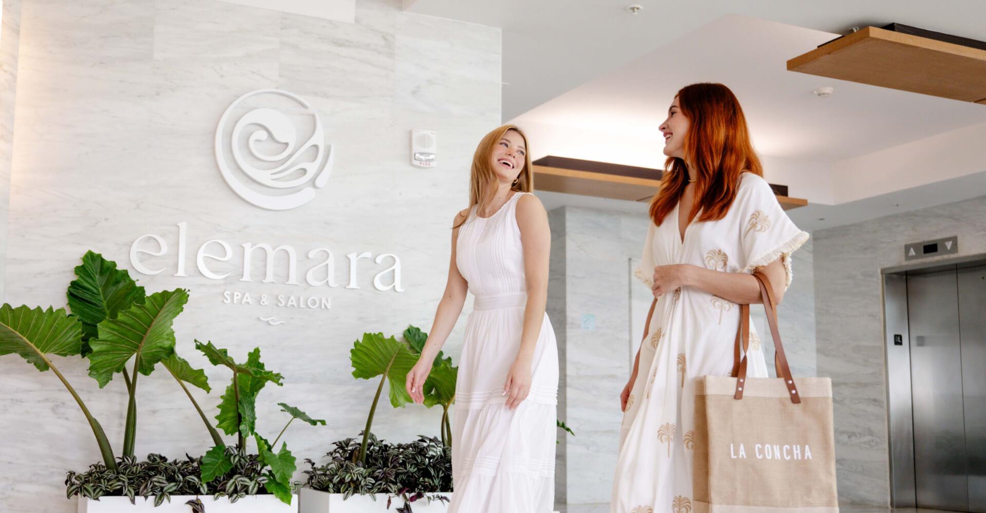 Two women walking and laughing together in Elemara Spa and Salon's lobby