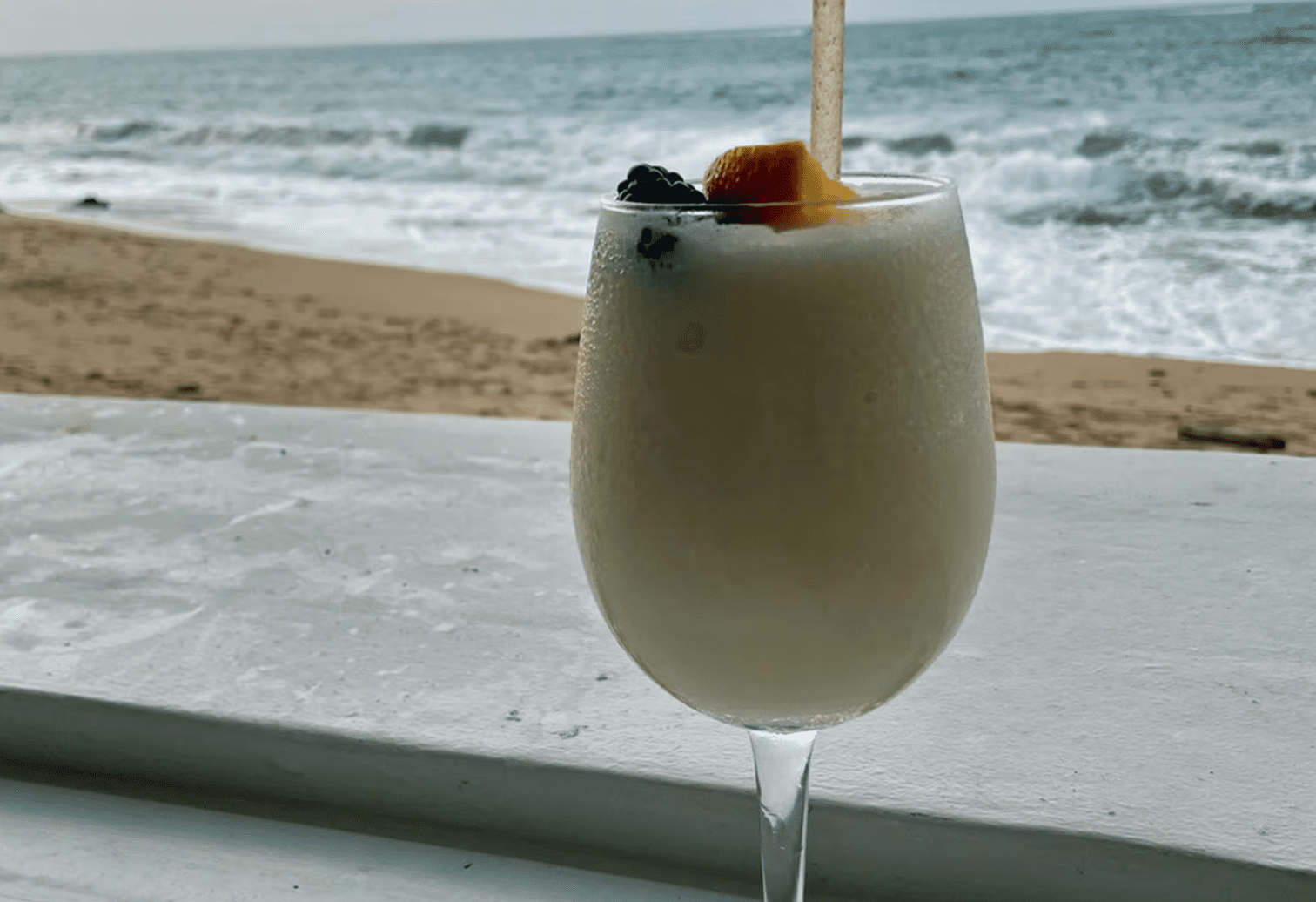 piña colada glass with the beach behind